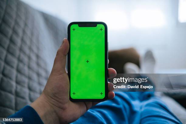 unrecognizable person lying on the sofa at home, while looking at mobile phone - chroma key stock-fotos und bilder