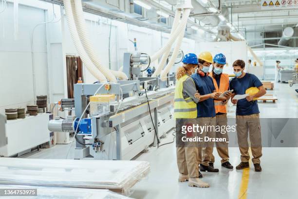 mitarbeiter in der fabrik tragen während des meetings gesichtsmasken - occupational safety and health stock-fotos und bilder