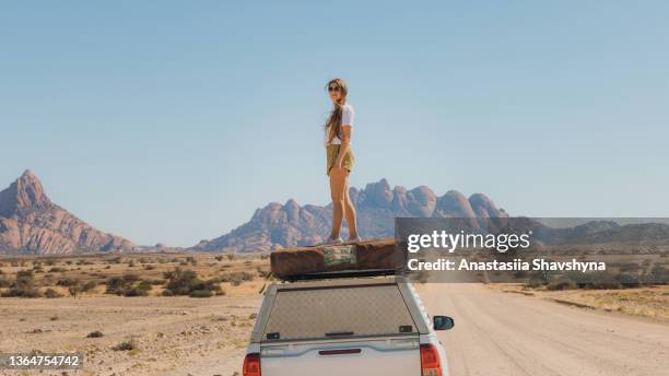 weibliche reisende, die auf dem wohnmobil bleiben und den blick auf die malerische landschaft in namibia genießen - kalahari stock-fotos und bilder