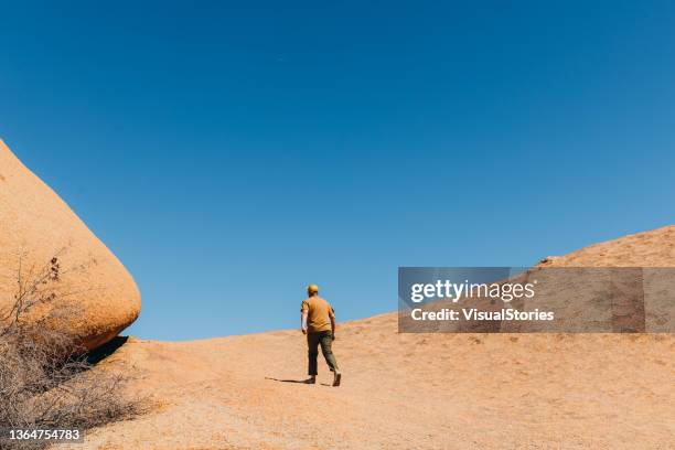 male traveler hiking along the rocky formations of spitzkoppe in namibia - spitzkoppe stock pictures, royalty-free photos & images