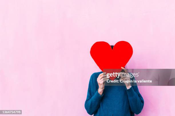unrecognizable woman holding a red heart shaped banner - scham stock-fotos und bilder