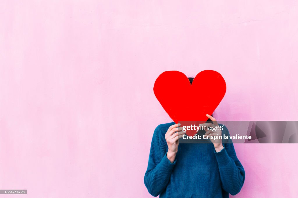 Unrecognizable woman holding a red heart shaped banner
