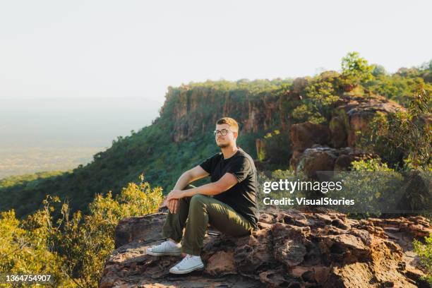 male traveler contemplating the scenic sunset from the top of the mountain in namibia - escarpment stock pictures, royalty-free photos & images