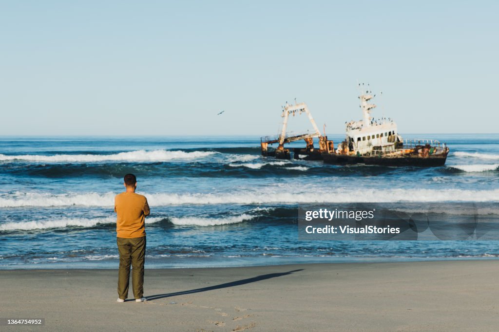 Male traveler exploring the scenic Skeleton coast with shipwreck
