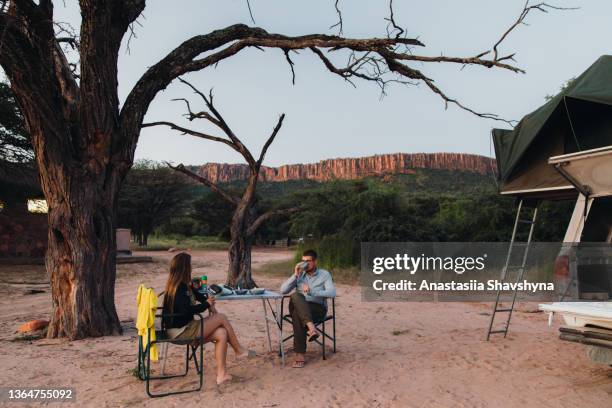 woman and man travelers contemplating sunset camping with mountain view in namibia - kalahari desert 個照片及圖片檔