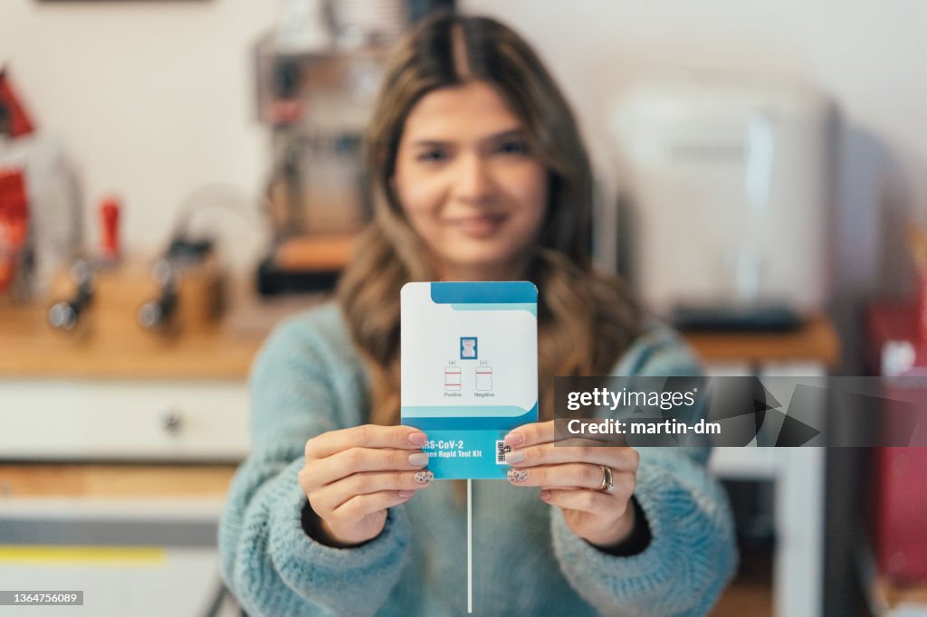Young woman showing SARS-COV-2 OMICRON negative test result to the camera