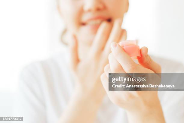 girl for protection applies hygienic lipstick to her lips - cream mouth stock-fotos und bilder