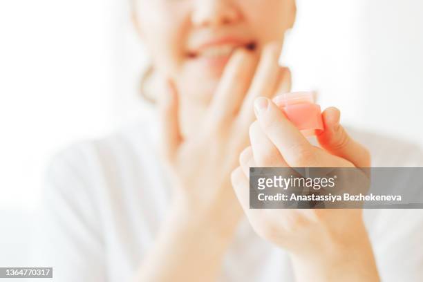 girl for protection applies hygienic lipstick to her lips - lippen stockfoto's en -beelden