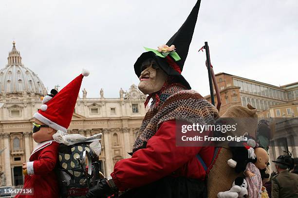 Woman dressed as the witch Befana presents sweets to children during the blessing held by Pope Benedict XVI in St. Peters square after the Epiphany...