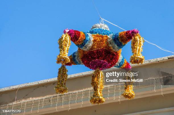 multicolored mexican christmas tinsel piñata hanging over a city street - tlaxcala imagens e fotografias de stock