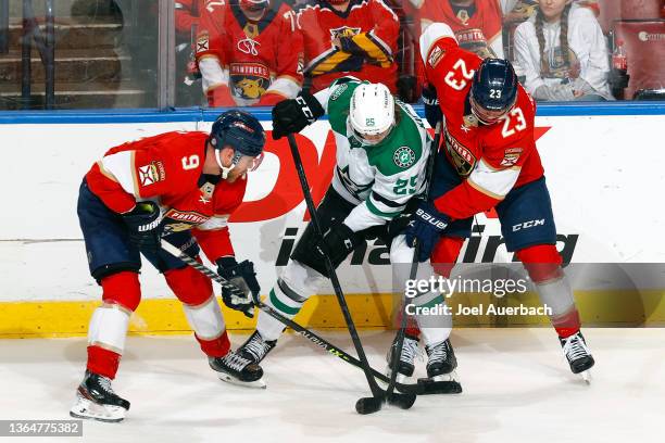 Sam Bennett and Carter Verhaeghe of the Florida Panthers battle Joel Kiviranta of the Dallas Stars for possession of the puck at the FLA Live Arena...