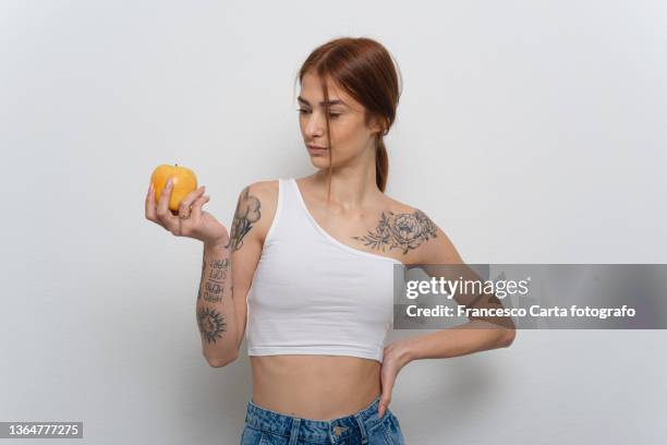 woman with tattoo eating an apple - weight off shoulder stock pictures, royalty-free photos & images