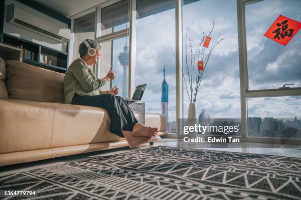 asian chinese senior woman using laptop video conference with her family members during chinese new year in living room of her apartment in city - air conditioner family stock pictures, royalty-free photos & images