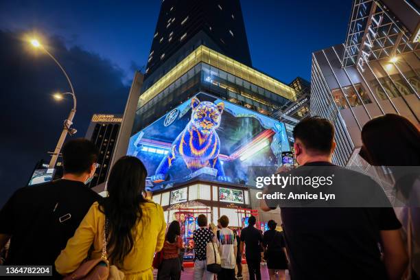 People taking photos of a three-dimensional tiger in a form of a hologram projection at the entrance of Pavilion Kuala Lumpur, on January 15, 2022 in...