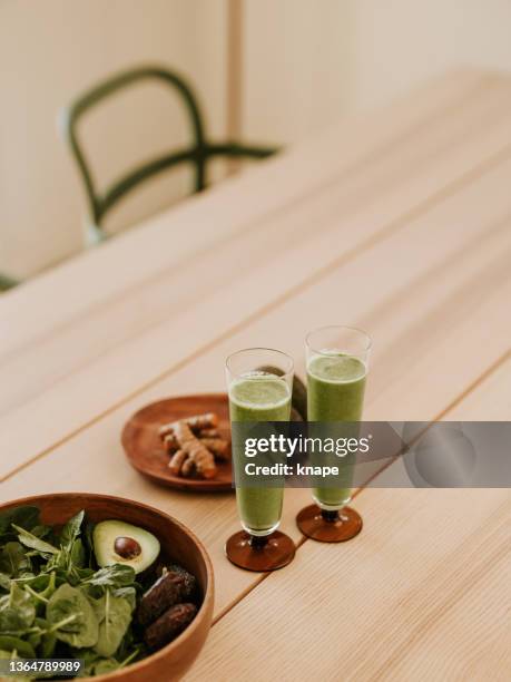 green smoothie vegetable drink in glass with healthy ingredients on table avocado turmeric - avocado smoothie stock pictures, royalty-free photos & images