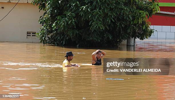 Local residents wade through a flooded street in the Tres Vendas neighborhood in Campos, 300 km north of Rio de Janeiro, Brazil, on January 6, 2012....