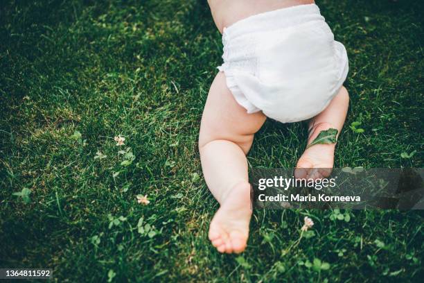 baby crawling on grass. - luier stockfoto's en -beelden