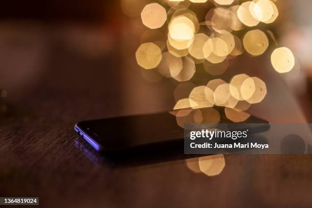 mobile phone on a glass table. in the background lights of a christmas tree. in the province of jaén andalusia, spain - smart phone on table stock pictures, royalty-free photos & images