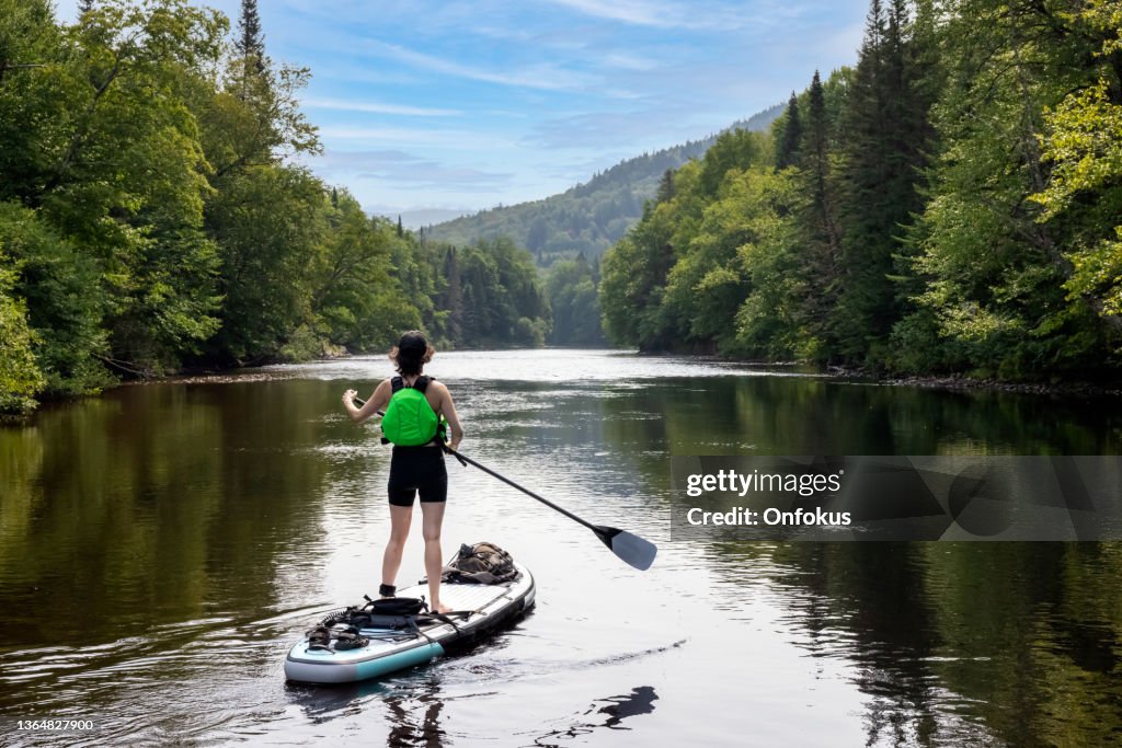 Mujer Paddleboarding en el río en verano