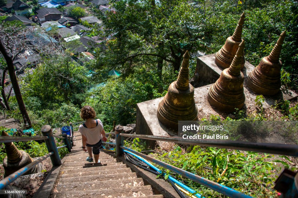 Young woman hiker climbing down on stone stairs to mountain peak, Wat Tham Suea (Tiger Cave Temple)