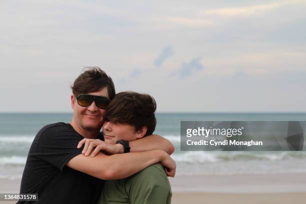awkward portrait of a dad hugging his teen son - embarrased dad stock pictures, royalty-free photos & images