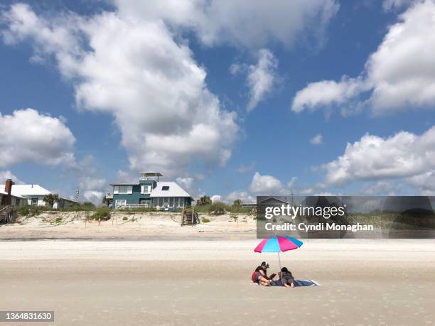 father and his daughter relaxing on the beach under an umbrella - shade45 stock pictures, royalty-free photos & images