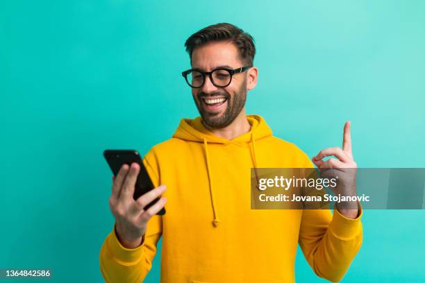 ¡recibí un mensaje! un hombre guapo con gafas y un teléfono móvil - fondo color fotografías e imágenes de stock