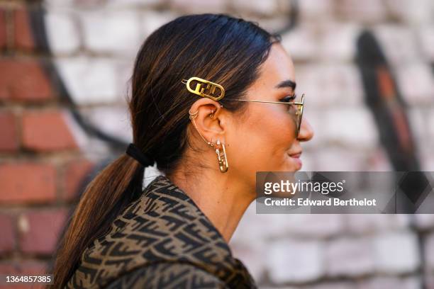 Tamara Kalinic wears aviator sunglasses, golden Fendi hair pins / brooch, golden long earrings, a golden necklace, outside the Fendi fashion show...
