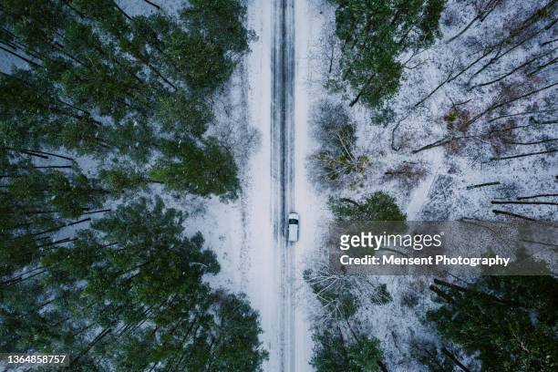 aerial view of white car on road in winter forest - reifenspur stock-fotos und bilder