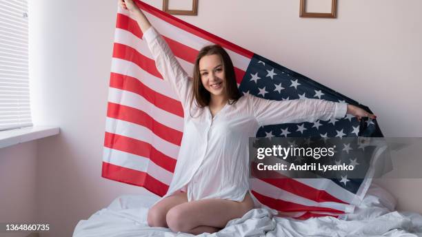 American flag day girl in the bedroom holds the symbol of independence of the united states in her hands behind her back. USA Independence Day