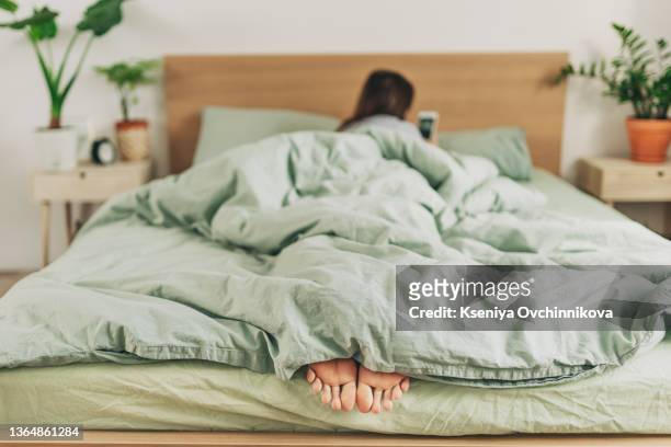 woman feet on the bed - sheet bedding stock-fotos und bilder