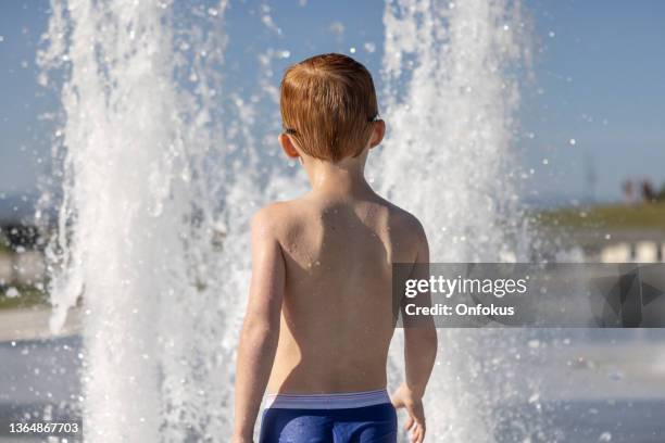 cute redhead boy playing in the water fountain, fontaine du quai paquet, lévis, quebec, canada - kids in undies stock pictures, royalty-free photos & images