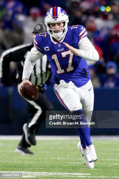 Josh Allen of the Buffalo Bills runs the ball for a first down against the New England Patriots during the first quarter in the AFC Wild Card playoff...