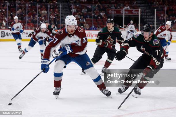 Compher of the Colorado Avalanche skates with the puck past Victor Soderstrom of the Arizona Coyotes during the first period of the NHL game at Gila...