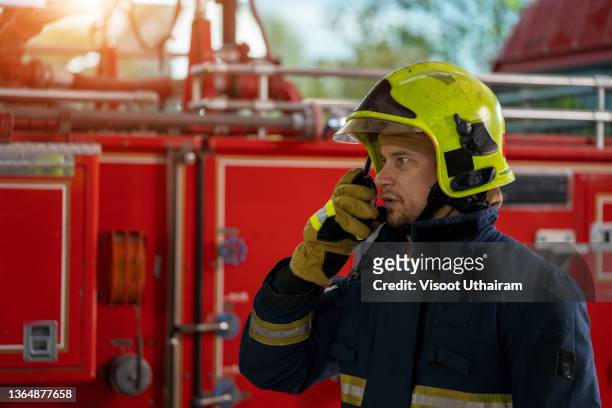 fireman wearing protective uniform and talking on the radio. - cb funk stock-fotos und bilder