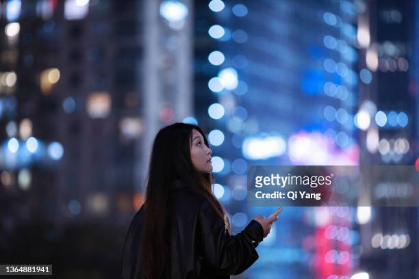 young asian woman using smartphone under skyscrapers in city - businesswoman under stock-fotos und bilder
