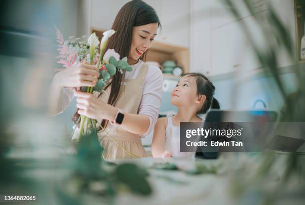 asian female florist bonding with daughter while working flower arrangement in kitchen - asia family stock pictures, royalty-free photos & images