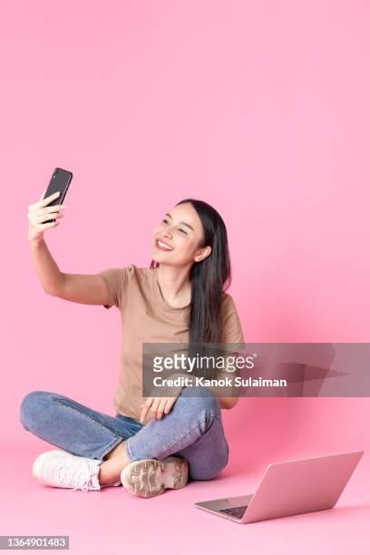 studio shot of young woman taking selfie - sitting and using smartphone studio stock pictures, royalty-free photos & images