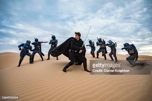 Star Wars cosplayer Austin Verberg as Luke Skywalker poses in a mock battle against a group of Nite Owl Mandos from Wonderfam Causeplay at Buttercup...