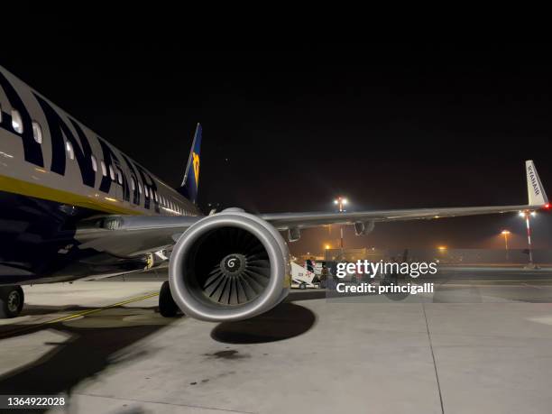 wein und motor eines ryanair-fahrzeugs mit passagieren, die aus dem flugzeug aussteigen. draußen, nacht. - plane engine stock-fotos und bilder