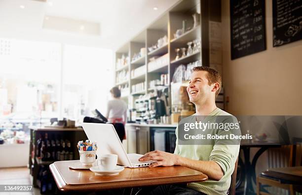 man using lap top in cafe laughing - newfriendship stock pictures, royalty-free photos & images