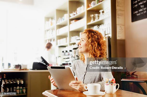 woman using wireless technology in cafe - newfriendship stock pictures, royalty-free photos & images