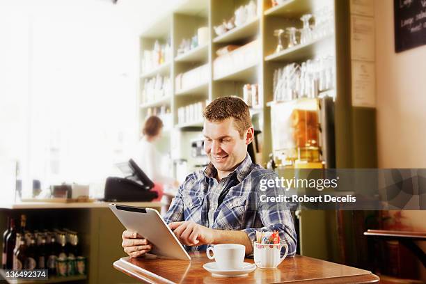 man using tablet in cafe - newfriendship stock pictures, royalty-free photos & images