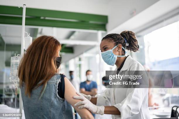 young woman getting vaccinated in a medical clinic - epidemiologia imagens e fotografias de stock