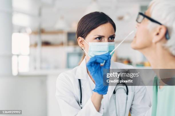 ärztin, die eine coronavirus-probe von einer älteren patientin nimmt - sinusitis stock-fotos und bilder
