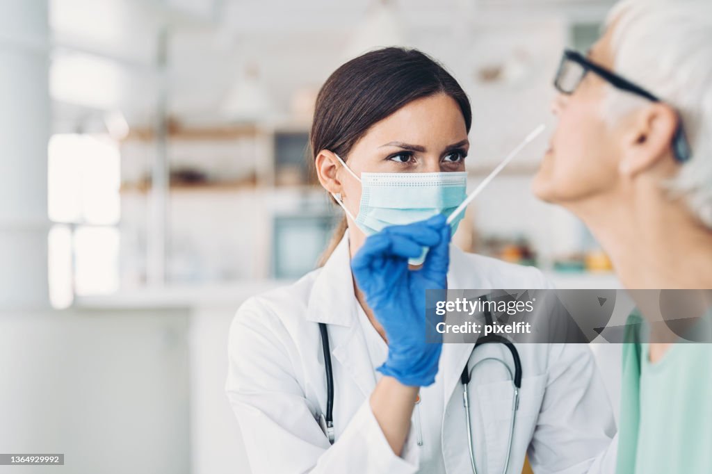 Medico donna che preleva un campione di coronavirus da un paziente anziano