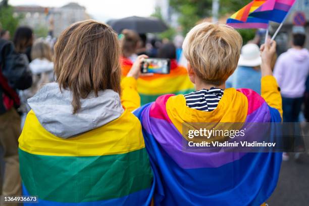 lgbt women wearing flags during pride event - sociale rechtvaardigheid stockfoto's en -beelden