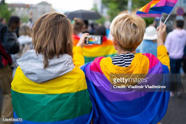 lgbt women wearing flags during pride event - pride march stock pictures, royalty-free photos & images