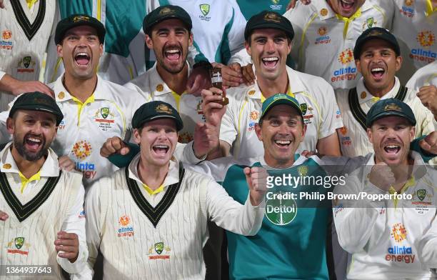 Pat Cummins holds a replica of the Ashes urn as he celebrates with Alex Carey, Mitchell Starc, Usman Khawaja, Nathan Lyon, Steve Smith, Justin Langer...