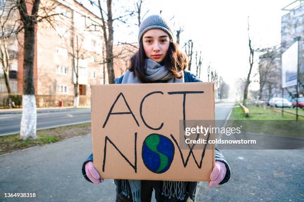 young activist holding sign protesting against climate change - fight for 15 protest stock pictures, royalty-free photos & images